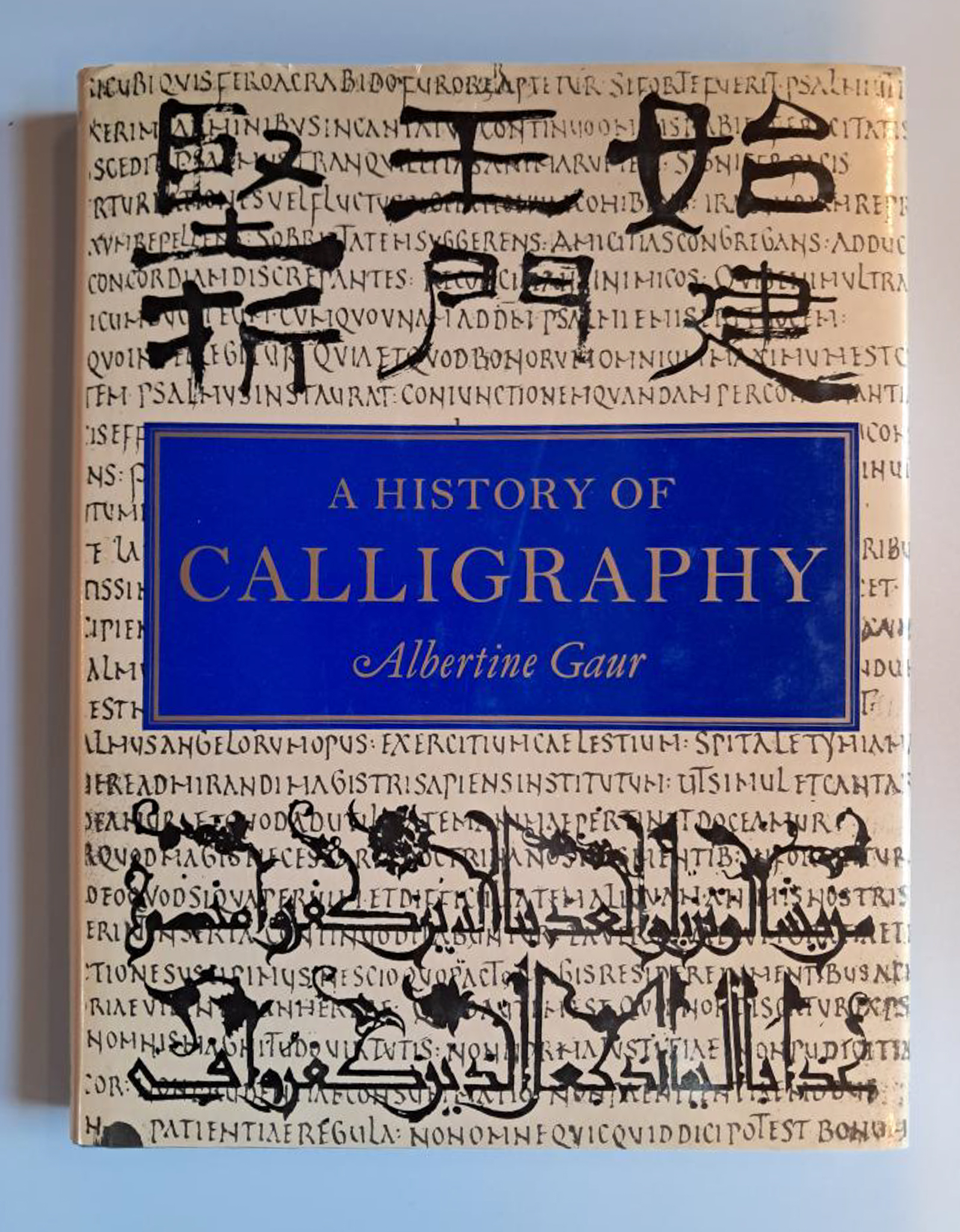 A History of calligraphy. A cream front cover with lots of calligraphic shapes. A block of dark blue in the centre displaying the title